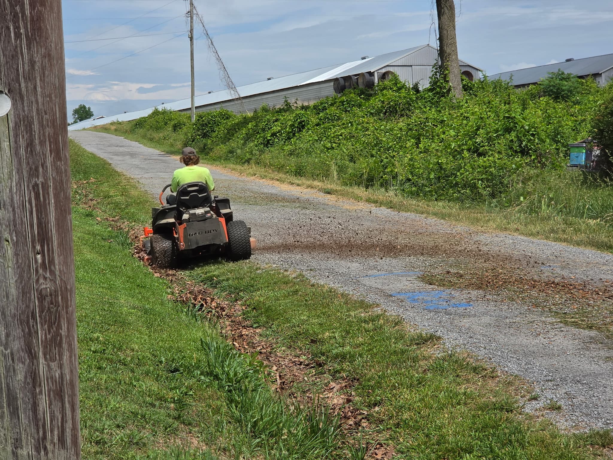 Riding mower trimming a long roadside strip on a Henagar route